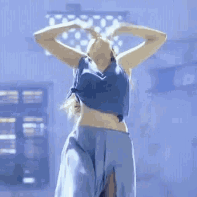 a woman in a blue top and blue pants is dancing .