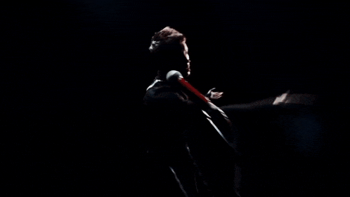 a man singing into a microphone with his hands outstretched