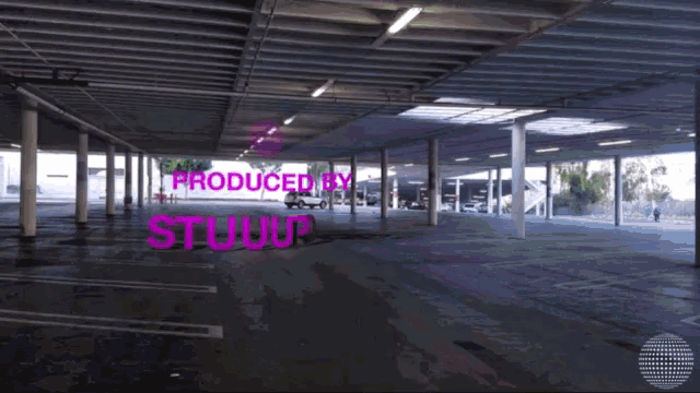 a purple sign in a parking garage says produced by stuart