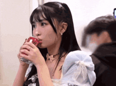 a woman is drinking a can of soda while sitting next to a man .