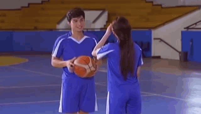 a man and a woman are playing basketball on a court .