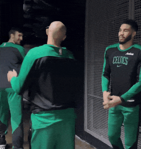 a man wearing a celtics jersey is talking to another man