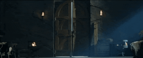 a man stands in front of a large door in a dark room .