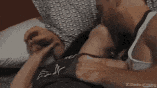 a man and woman are laying on a bed holding hands and kissing .