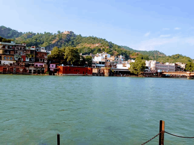 a large body of water with buildings on the shore and mountains in the background