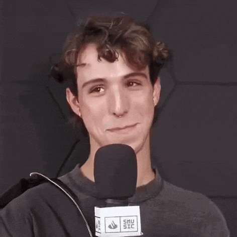 a young man is laughing while holding a microphone .