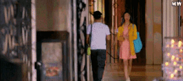a man and a woman are walking down a hallway together .