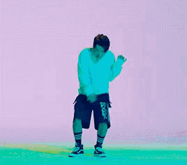 a man in a white shirt and black shorts is dancing in front of a pink background .