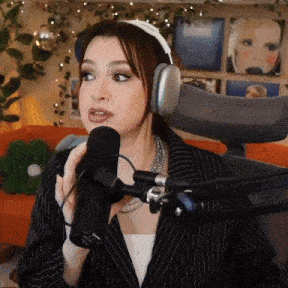 a woman wearing headphones and a suit is speaking into a microphone