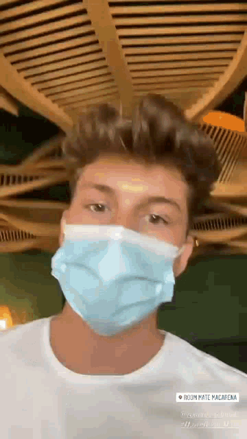 a man wearing a blue face mask is standing in a room .