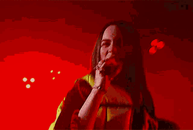 a woman singing into a microphone on a stage with red lights behind her
