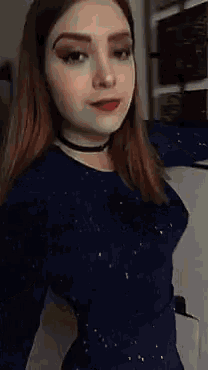 a woman is taking a selfie with her arms outstretched and wearing a choker .