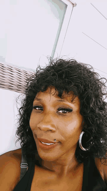 a woman with curly hair and hoop earrings smiles