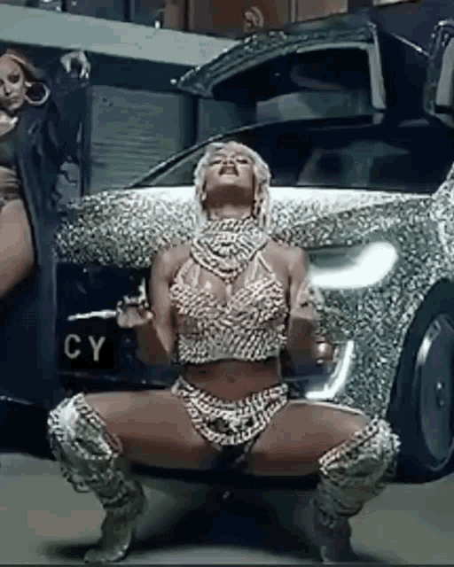 a woman is squatting in front of a car with the license plate cy on it