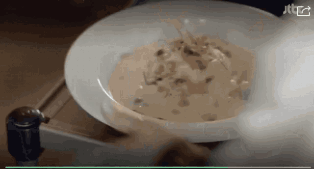 a person is holding a bowl of soup with a jtc logo in the corner