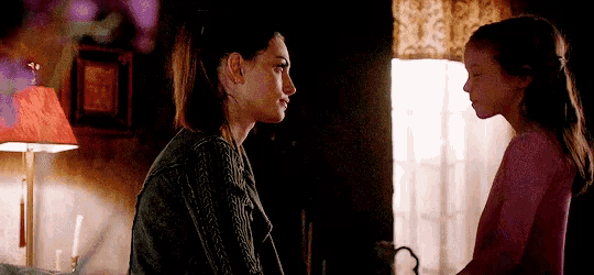 a woman and a little girl are looking at each other in a room
