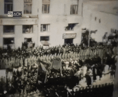 a crowd of people are gathered in front of a building with a sign that says 24 ack on it
