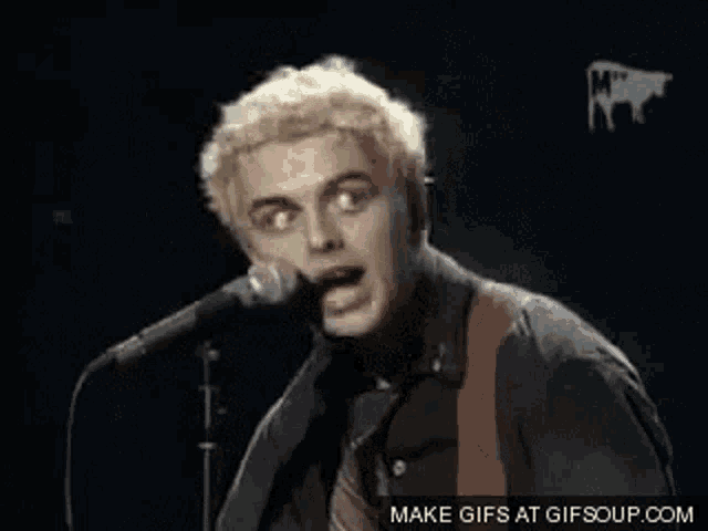 a man is singing into a microphone while holding a guitar .