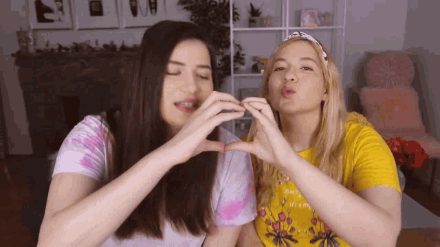 two girls are making a heart shape with their hands and one has a shirt that says i 'm a princess