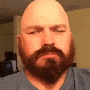 a bald man with a beard is making a face .