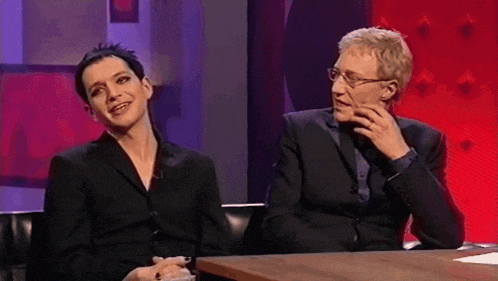 a man and a woman are sitting at a table and smiling