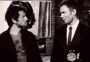 two men are standing next to each other in front of a sign that says ' e '