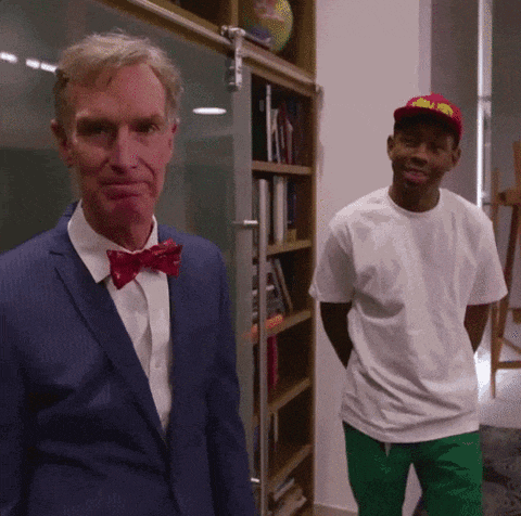 a man in a suit and bow tie stands next to another man in a white shirt
