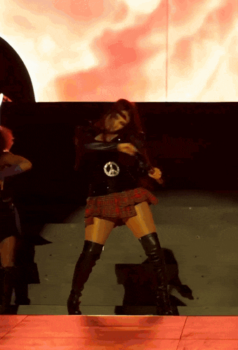 a woman in a plaid skirt and thigh high boots is dancing on a stage