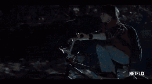 a young boy is riding a bike in the dark in a netflix trailer .