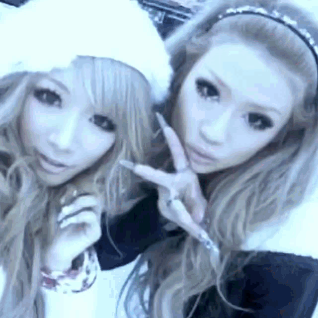 two young women are posing for a picture together and making peace signs .