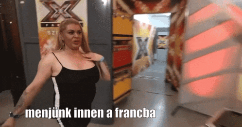a woman in a black tank top is standing in front of a sign that says x factor