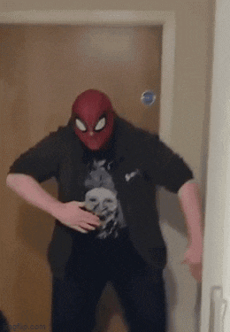a man wearing a spider man mask is standing in a doorway