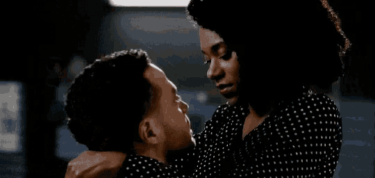 a man and a woman are kissing in a dark room . the woman is holding the man 's neck .