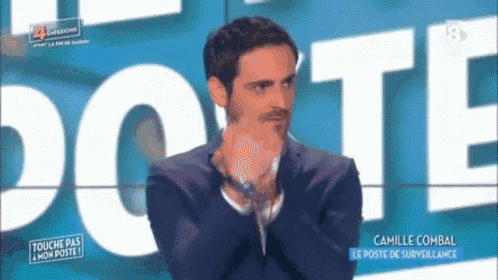 a man in a suit is clapping his hands in front of a sign that says dote