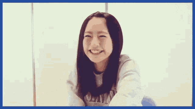 a woman wearing a grey sweatshirt with the word champion on it smiles