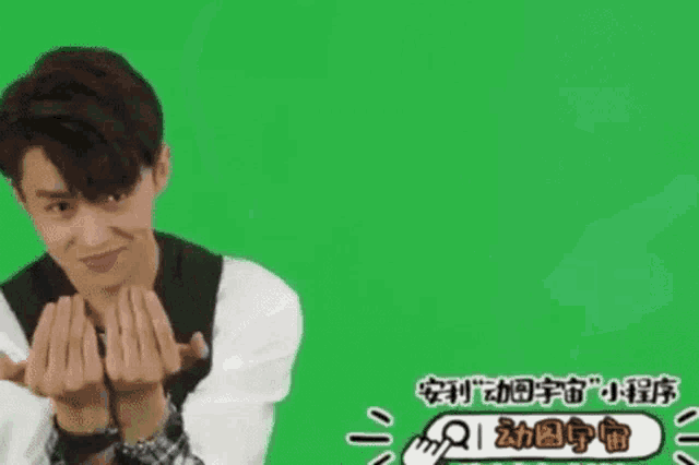 a young man is making a face in front of a green screen .