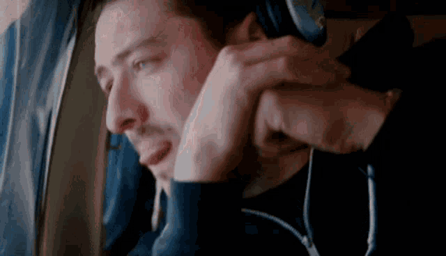 a man is wearing headphones on a plane while crying .
