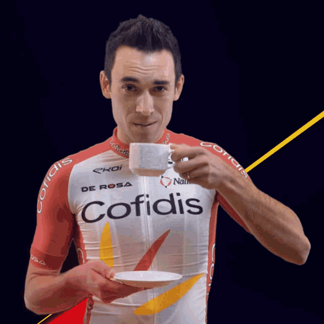 a man wearing a cofidis jersey drinks from a cup