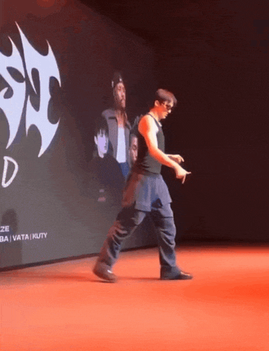 a man is walking on a red carpet in front of a large screen that says ' d ' on it