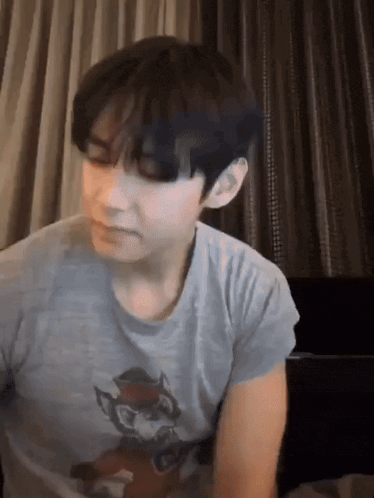 a young man wearing a grey t-shirt with a cat on it