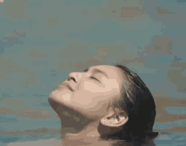 a woman is swimming in a pool with her head above the water and her eyes closed .