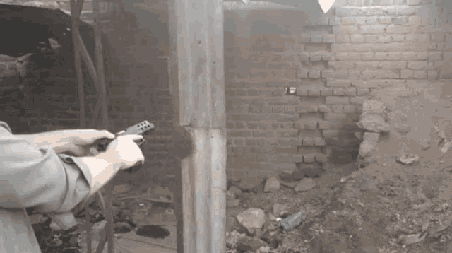a man holds a remote control in front of a brick wall