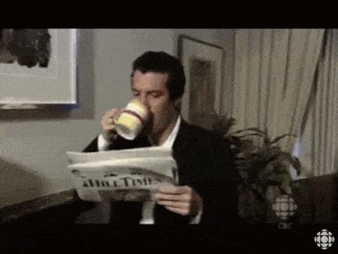 a man drinking a cup of coffee while reading a newspaper called about time