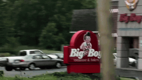a big boy restaurant and bakery sign in front of a busy street