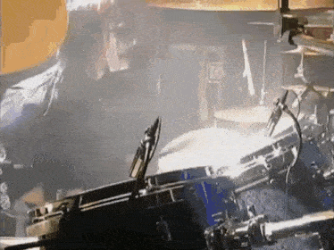 a man is playing drums in a dark room with a microphone in front of him .