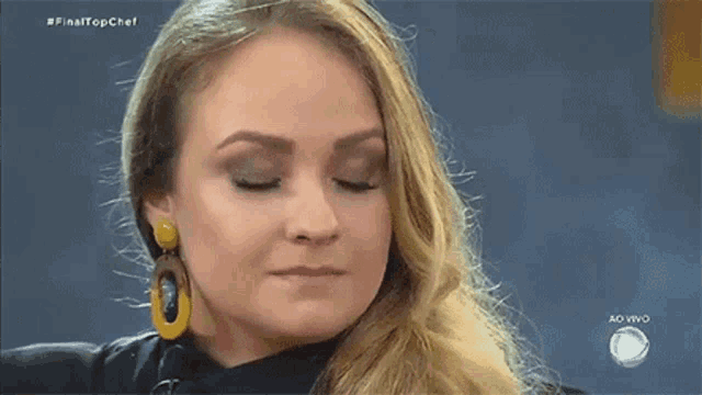 a close up of a woman 's face with her eyes closed wearing yellow earrings .