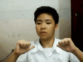 a young boy in a white shirt is making a funny face with his hands
