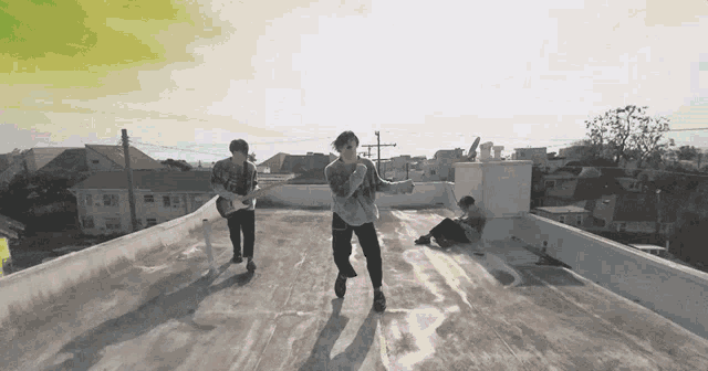 a man playing a guitar on a rooftop while another man watches