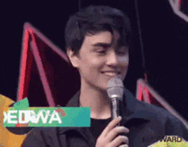 a man is smiling while holding a microphone with a sign that says edwa on it