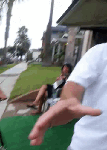 a man in a white shirt is standing in front of a man in a wheelchair smoking a cigarette